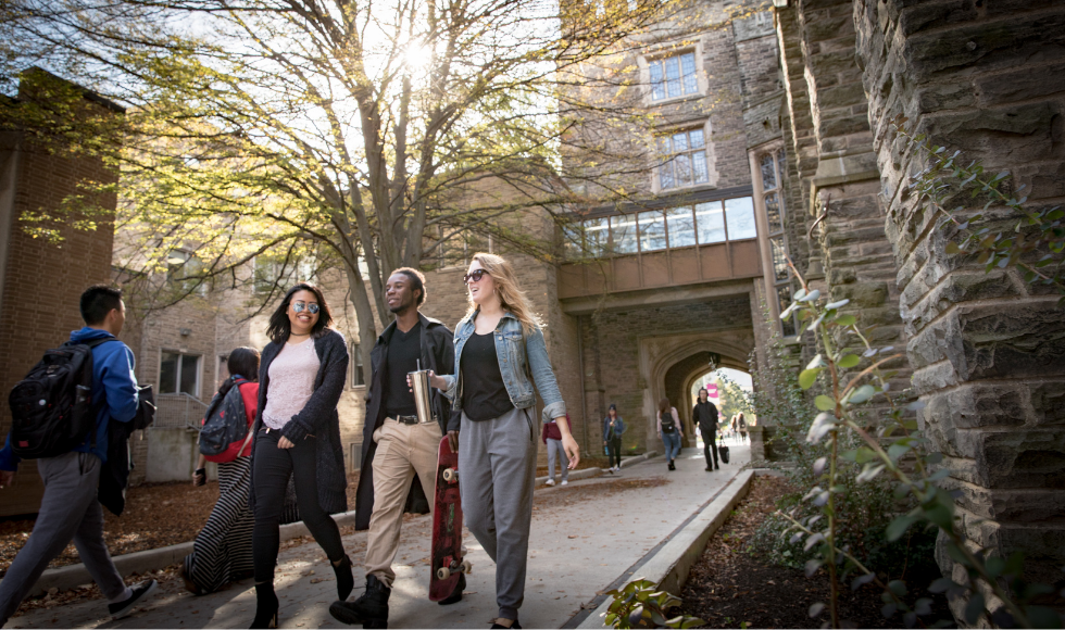 A group of students walk through the archway dividing University Hall and Gilmour Hall on the McMaster University campus.