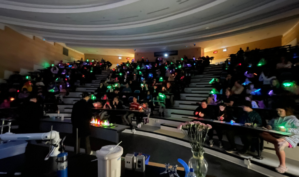 Image of a lecture hall filled, with people with glowing lights