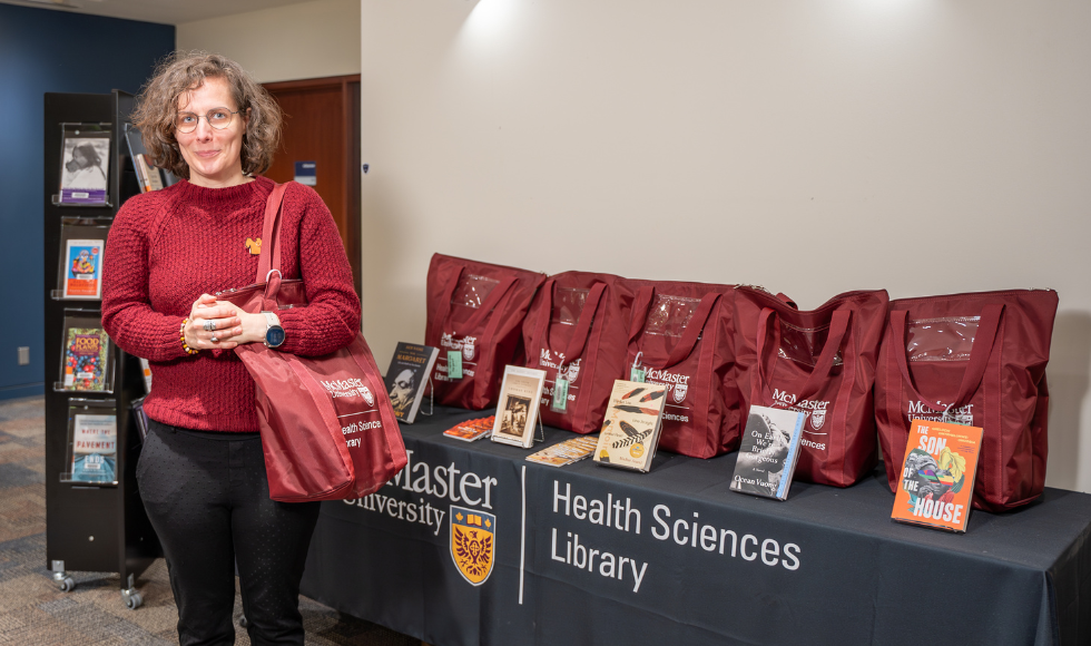 Laura Banfield stands in the Health Sciences Library beside a display of book club kits.