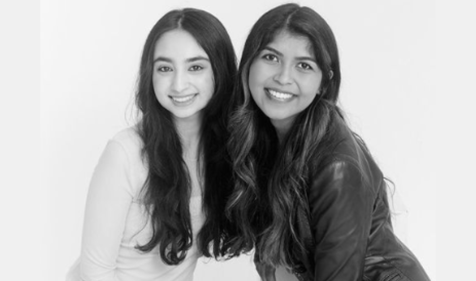 Black and white, Inaya Yousaf and Vikita Mehta smiling, leaning toward each other