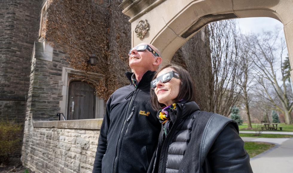 Two people wearing McMaster-branded solar eclipse glasses looking up to the sky