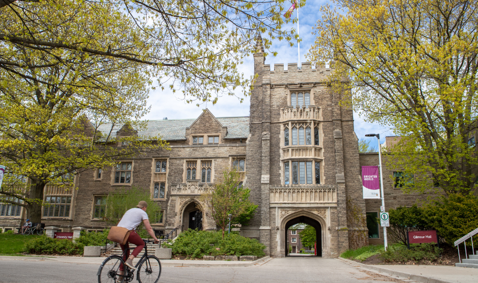 The exterior of McMaster's University Hall on a spring day. A person on a bicycle is in the foreground.