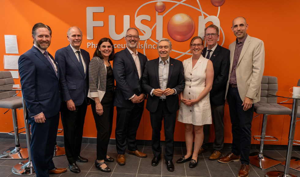 Eight people standing in front of a sign that reads, ‘Fusion Pharmaceuticals Inc.’