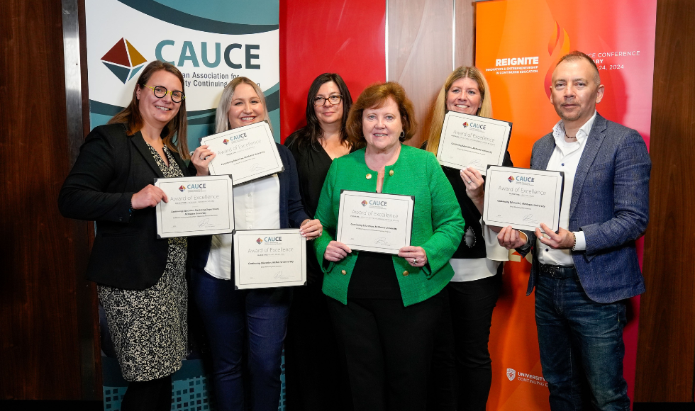 A group of six smiling people in front of a backdrop that reads CAUCE, holding up certificates of their awards.