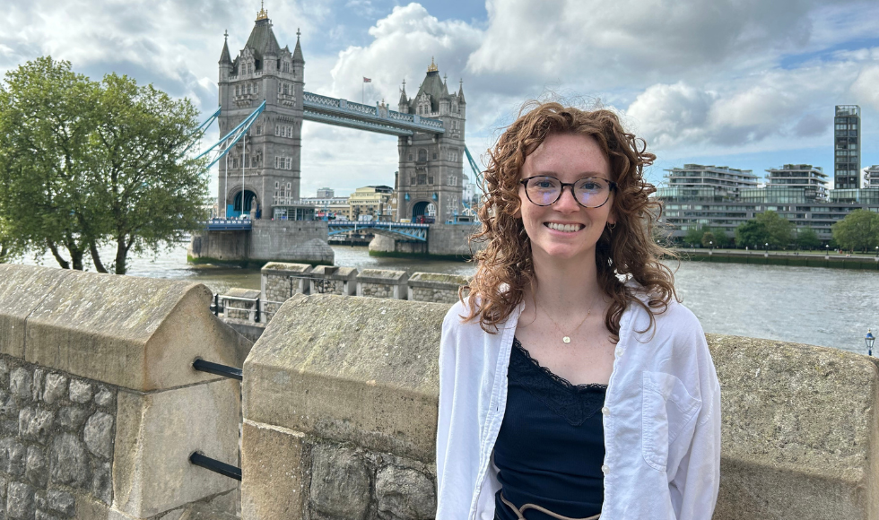 Chloe Valentine smiling at the camera. Behind her is the London Bridge.