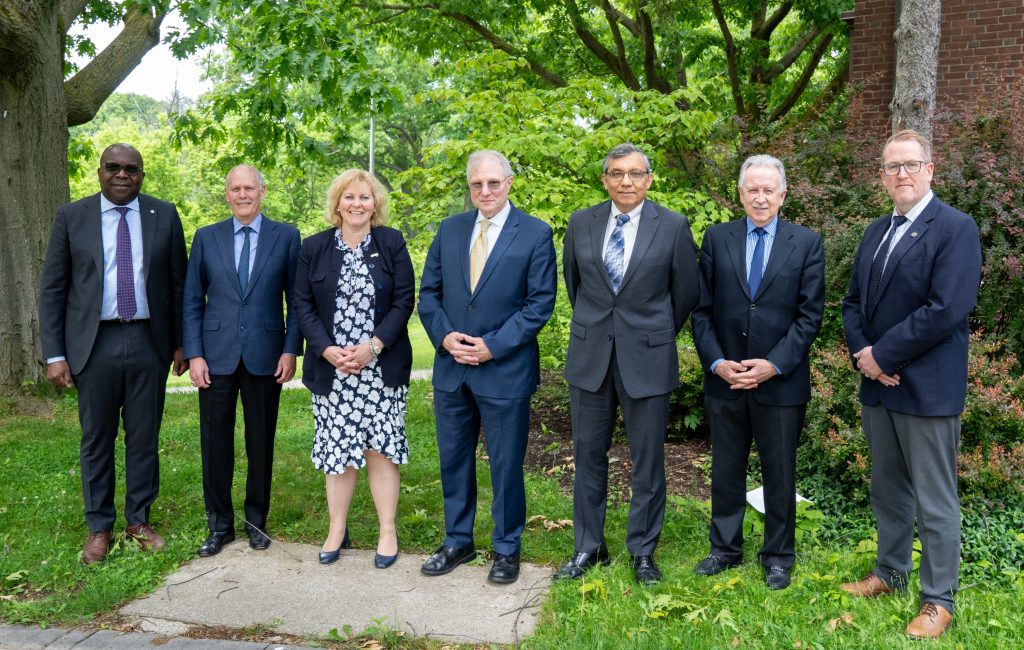 Group of university leaders standing outdoors, smiling at the camera