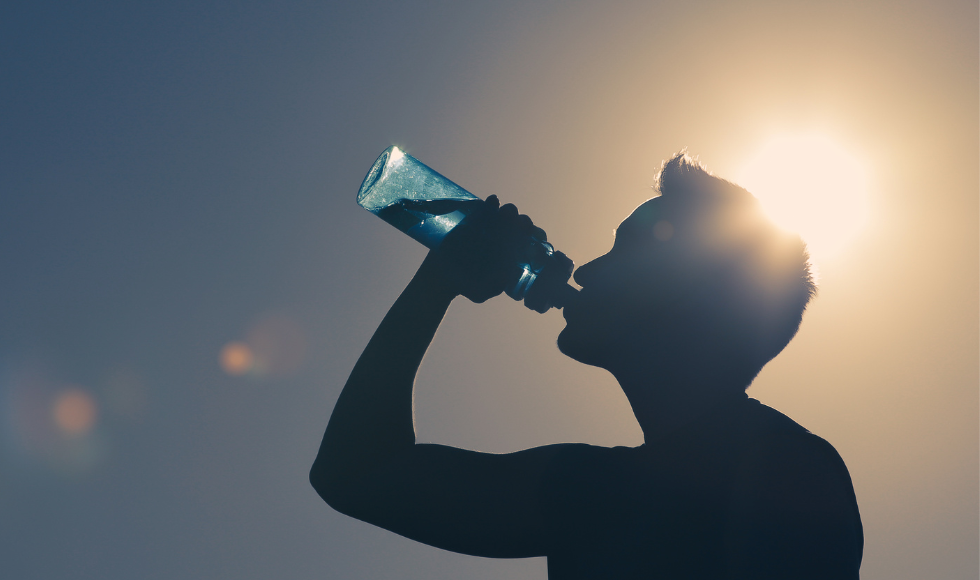 Silhouette of a person drinking water, backlit by the sun