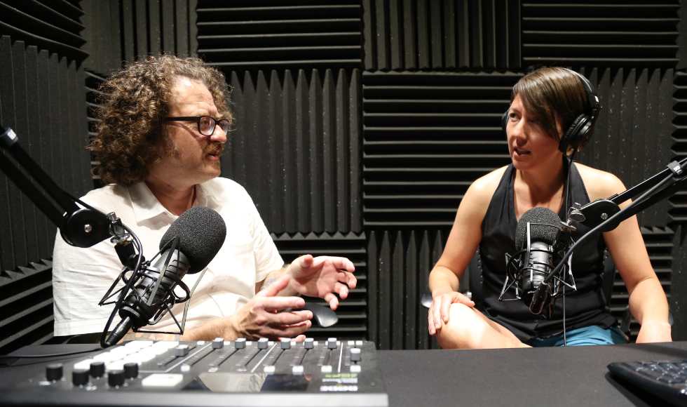 Two people sitting beside each other in a podcast recording studio