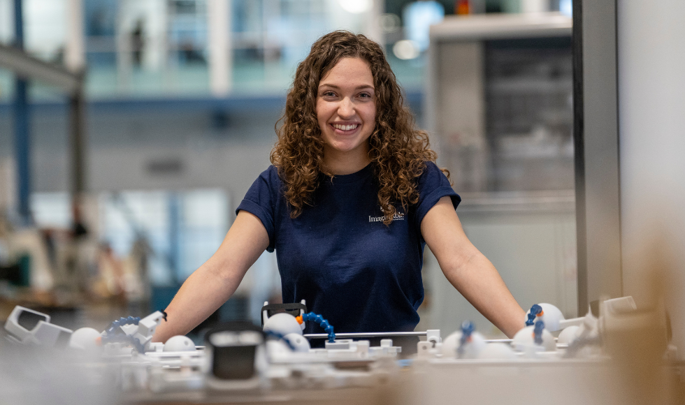 Lianna Genovese smiling directly at the camera while standing in front of a table that has an assistive device on it.