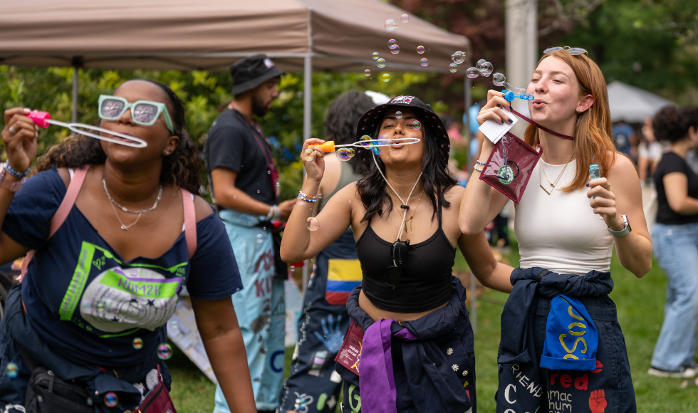 Three smiling people blow bubbles