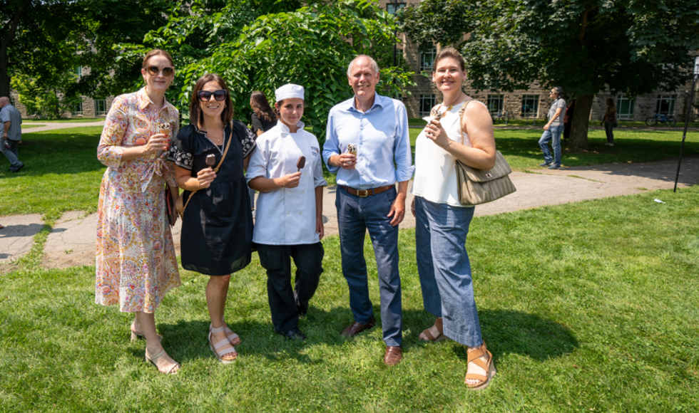 President Farrar and four staff members are holding ice cream and smiling on BSB field