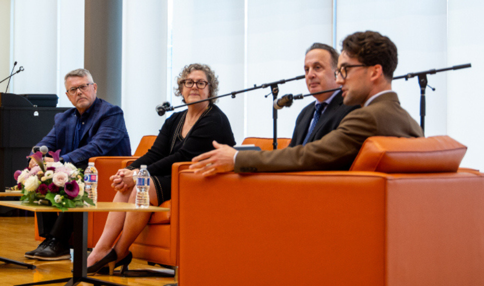 Four panellists sit in a row of armchairs for a discussion.