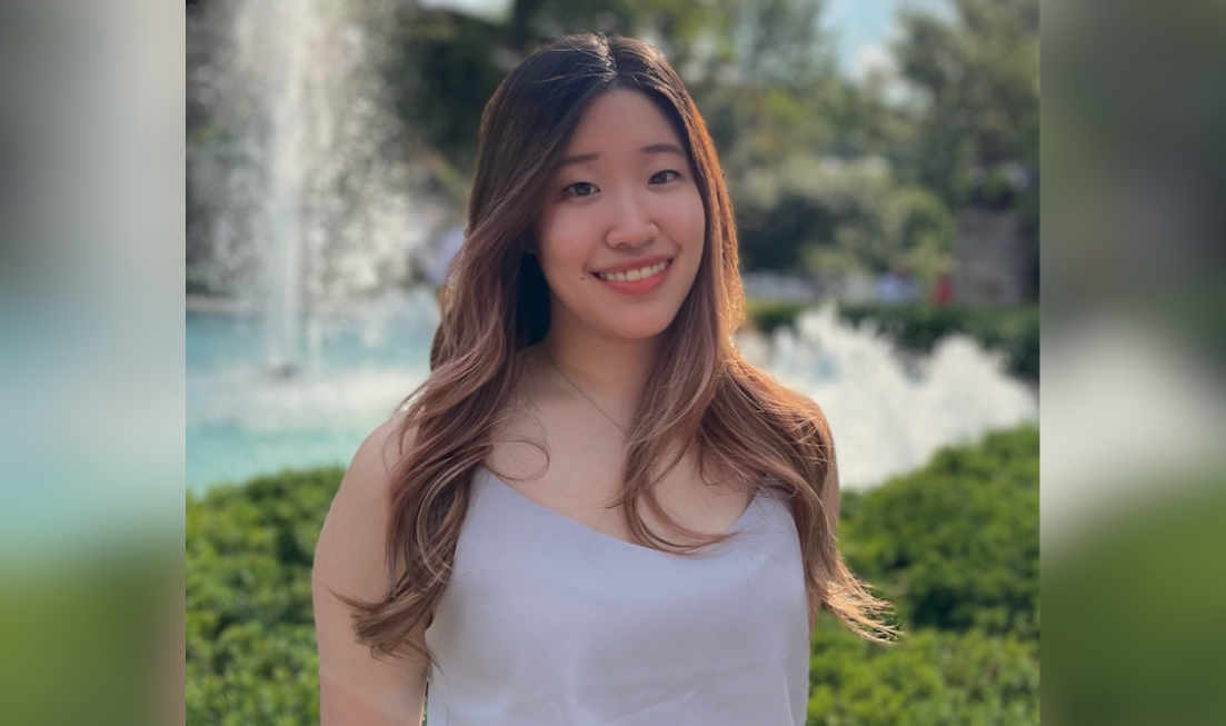 Ashley Jong in front of a water fountain surrounded by greenery.