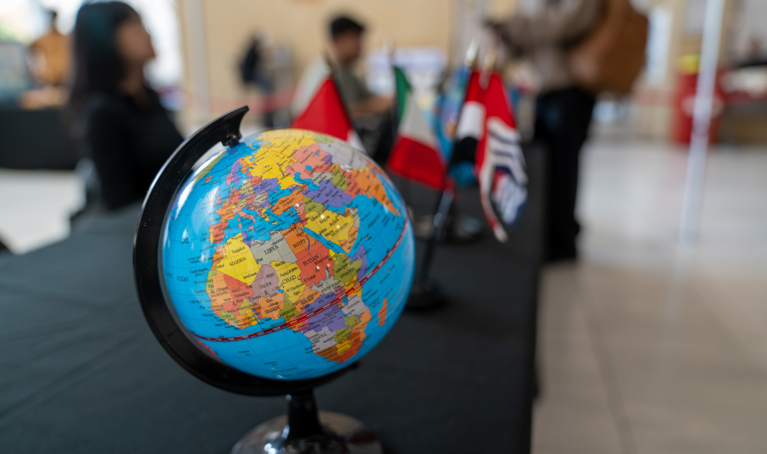 A small globe on a table with Cultural Fest and flags in the background.