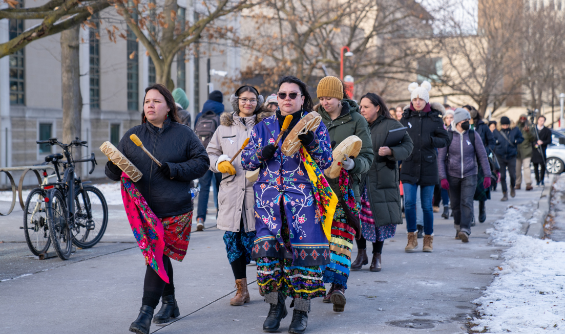 Led by Indigenous women from the Kindred Spirits drum circle, a group of people walks across campus at the beginning of the Dec. 6 memorial walk.