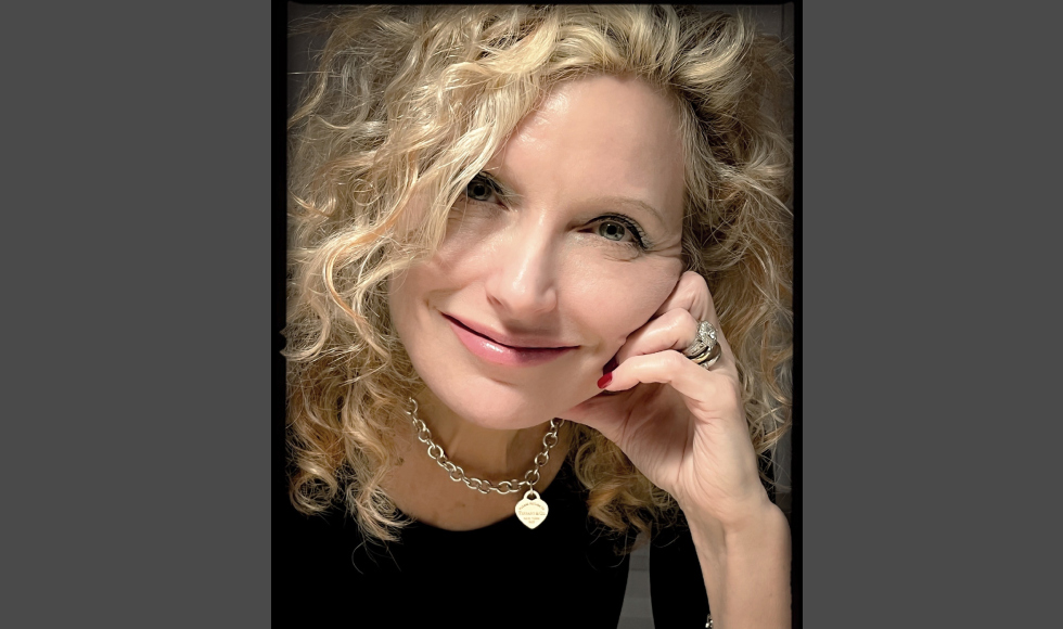 Headshot of a smiling Ann Heesters, with her chin resting on one hand.