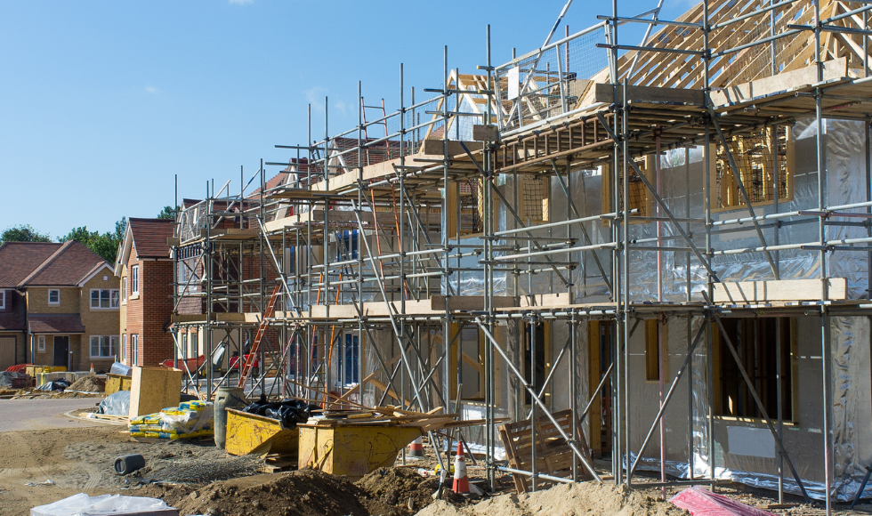 A row of houses under construction on a sunny day.