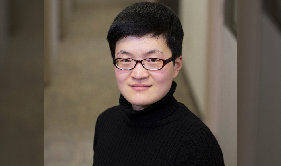 Head and shoulders of a person with short-cropped dark hair, glasses, wearing a black turtleneck