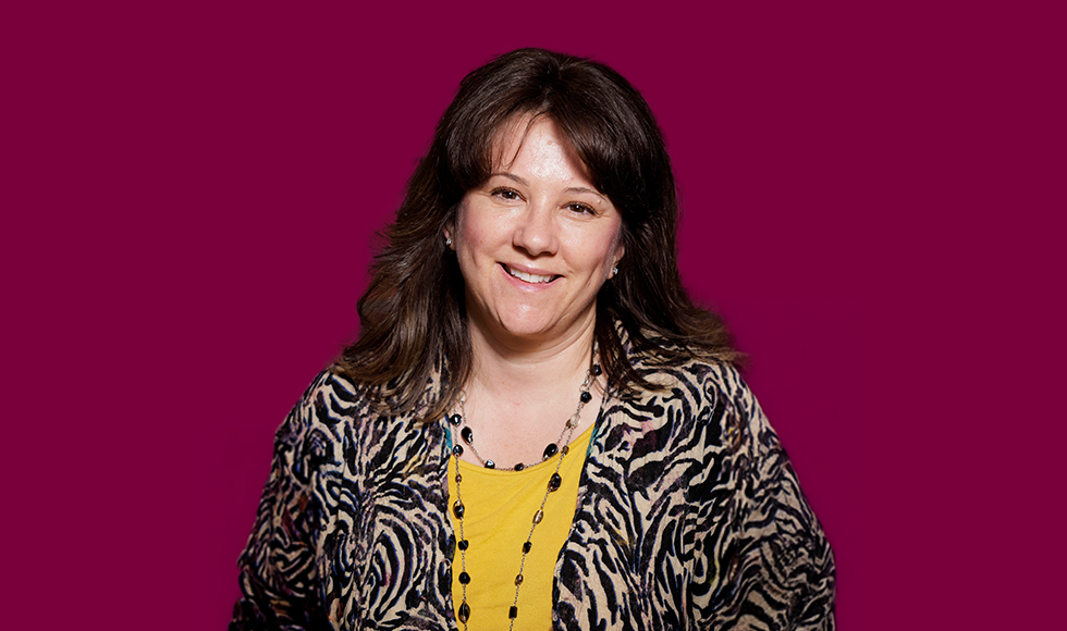 Head and shoulders of smiling Natasha Estey against a maroon backdrop.