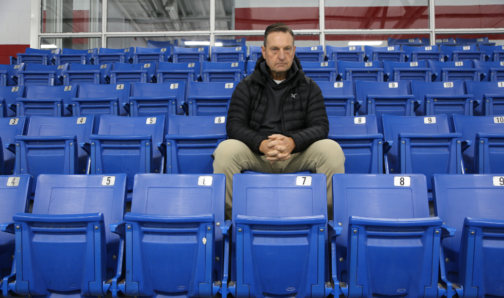 A man sits among rows of empty bleachers.