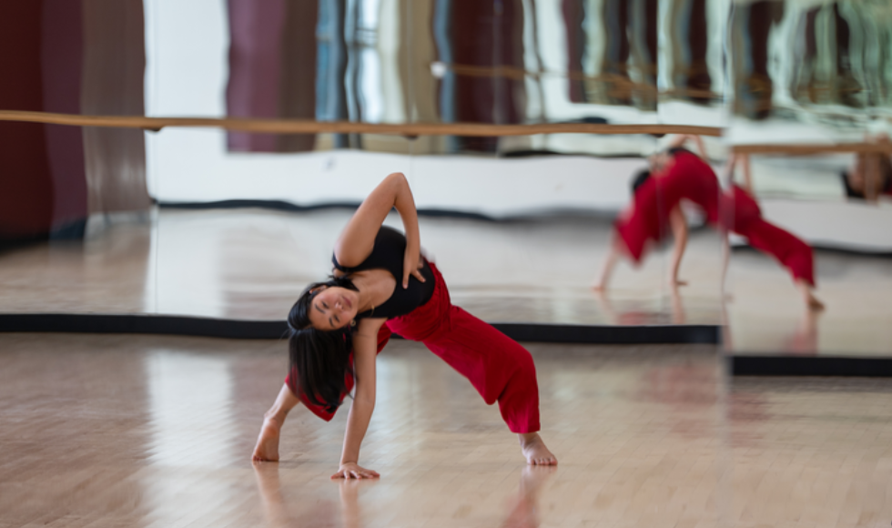 A woman in dance clothes dances in a studio.