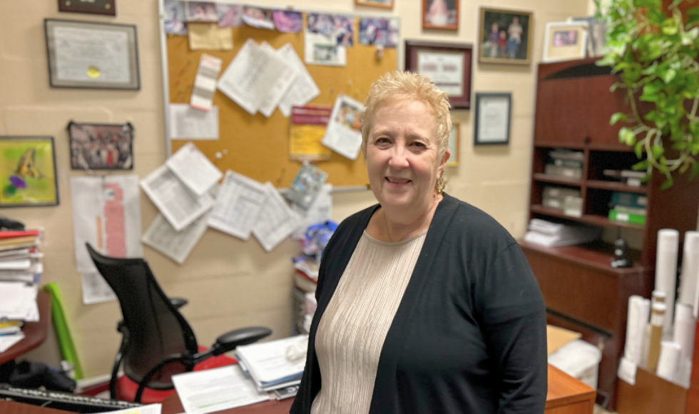 Karen Gourlay stands in her office in front of the desk, smiling to camera.