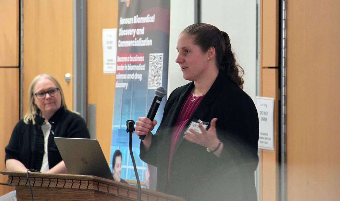 Sara andres speaks into a microphone at a podium indoors.