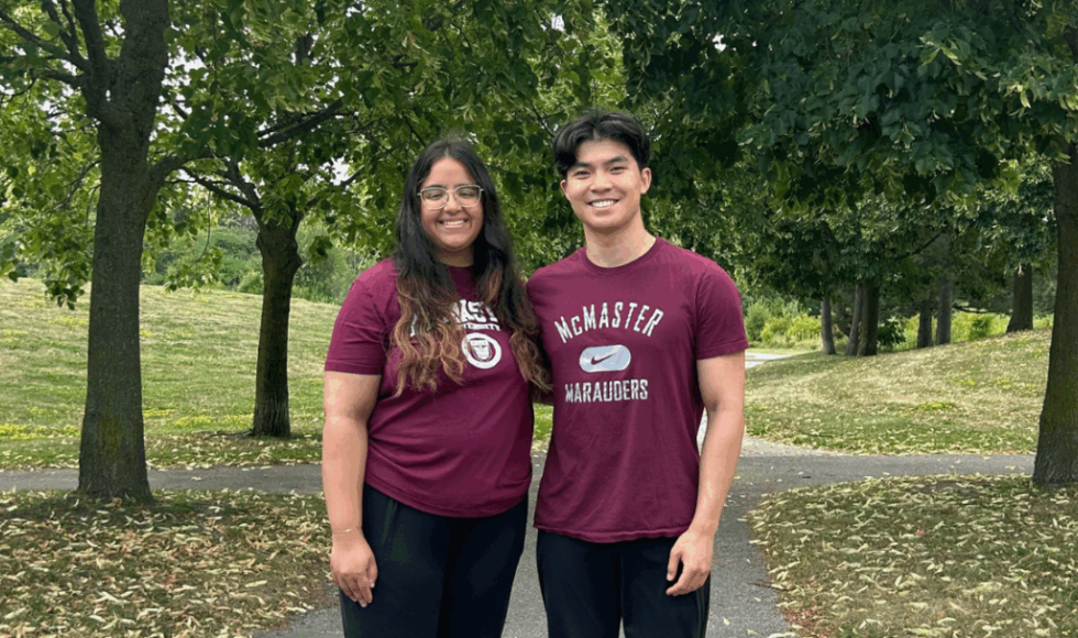 Myra and Ryan pose in a park wearing McMaster t-shirts.