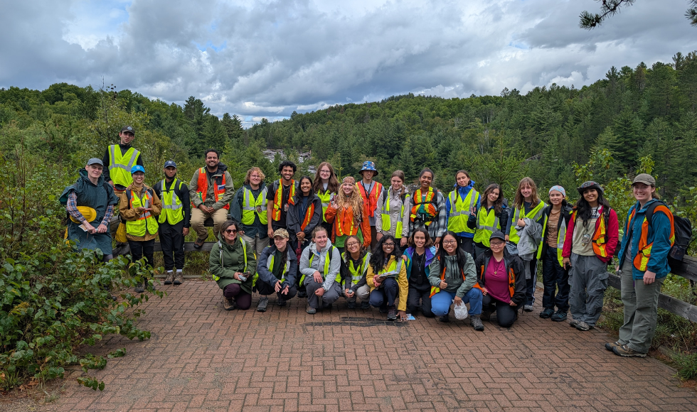 A group of people in hi-vis vests stands at a green lookout point.