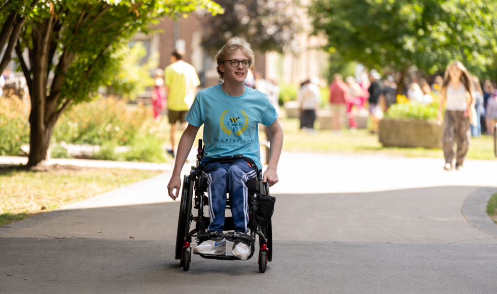 A man in a wheelchair moves along a sidewalk.